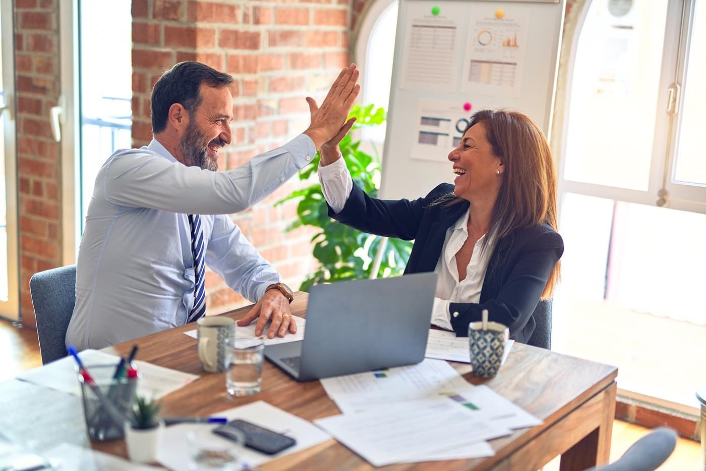 Two people high-fiving after successfully investing in luxury real estate.