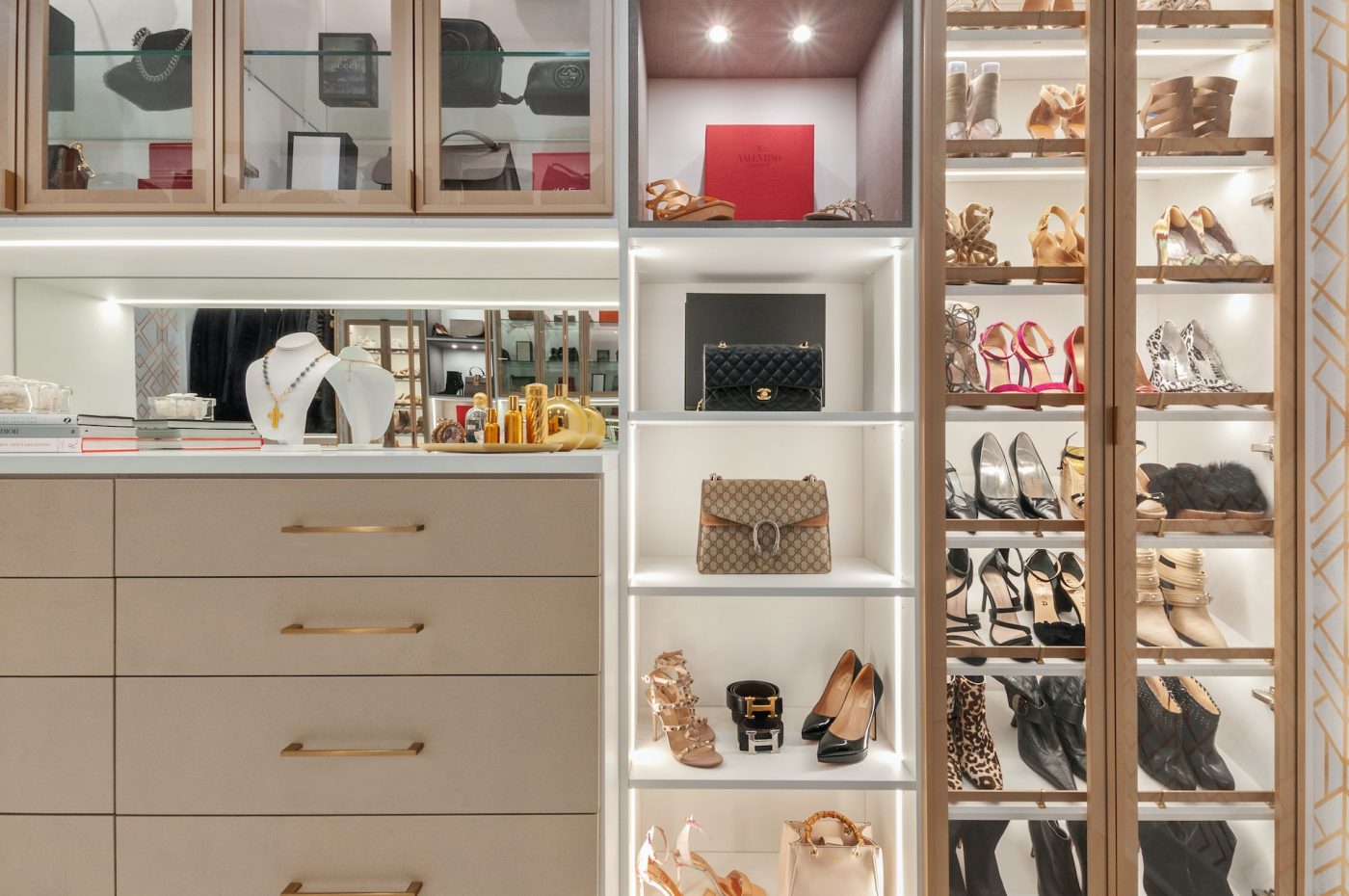 A walk-in closet with different shoes and bags on display.