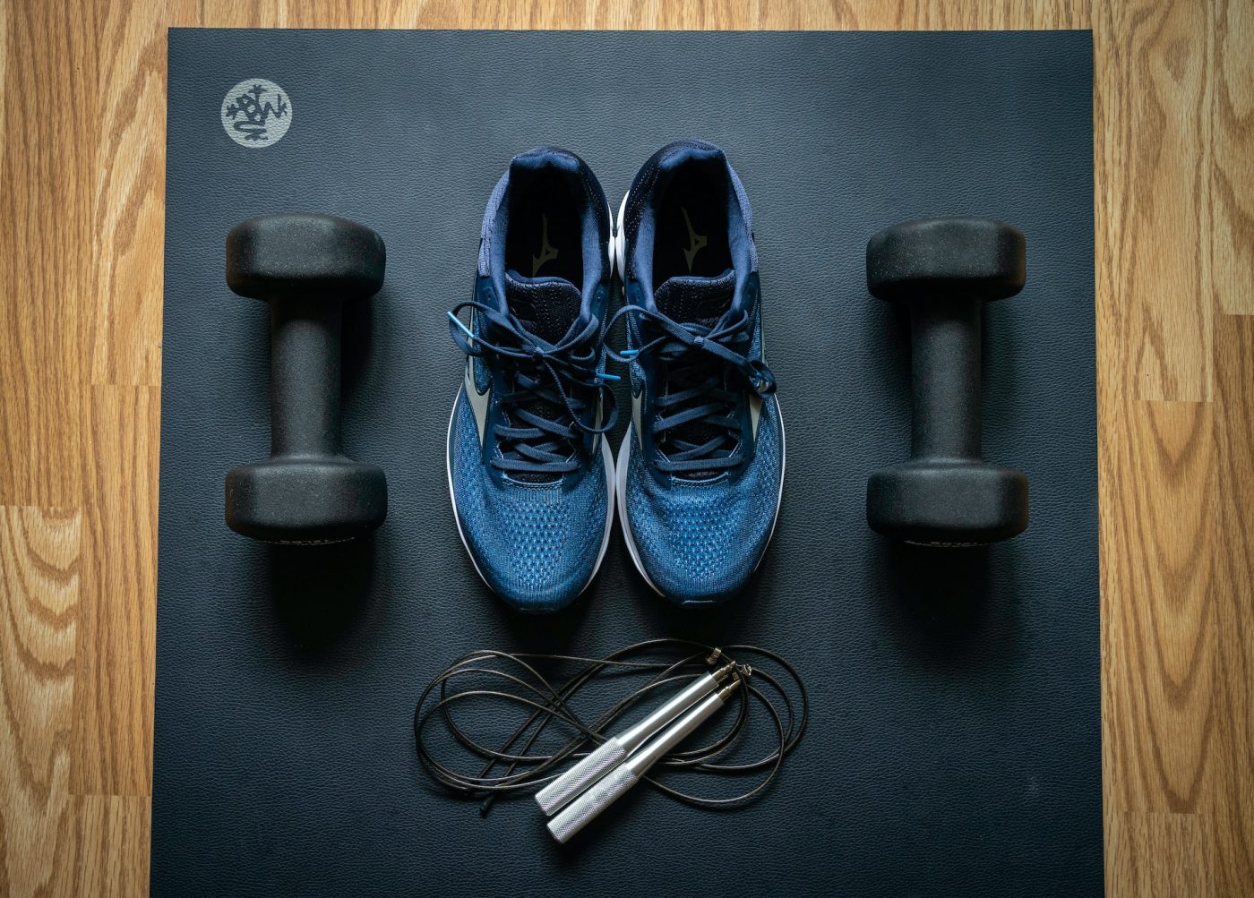 Blue sneakers and exercise equipment on a wooden floor.
