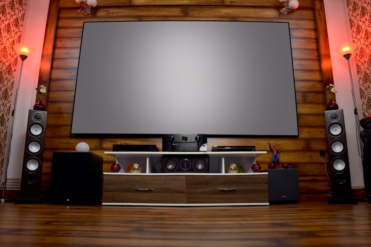 A large TV with different speakers all around it at a personal home theater.