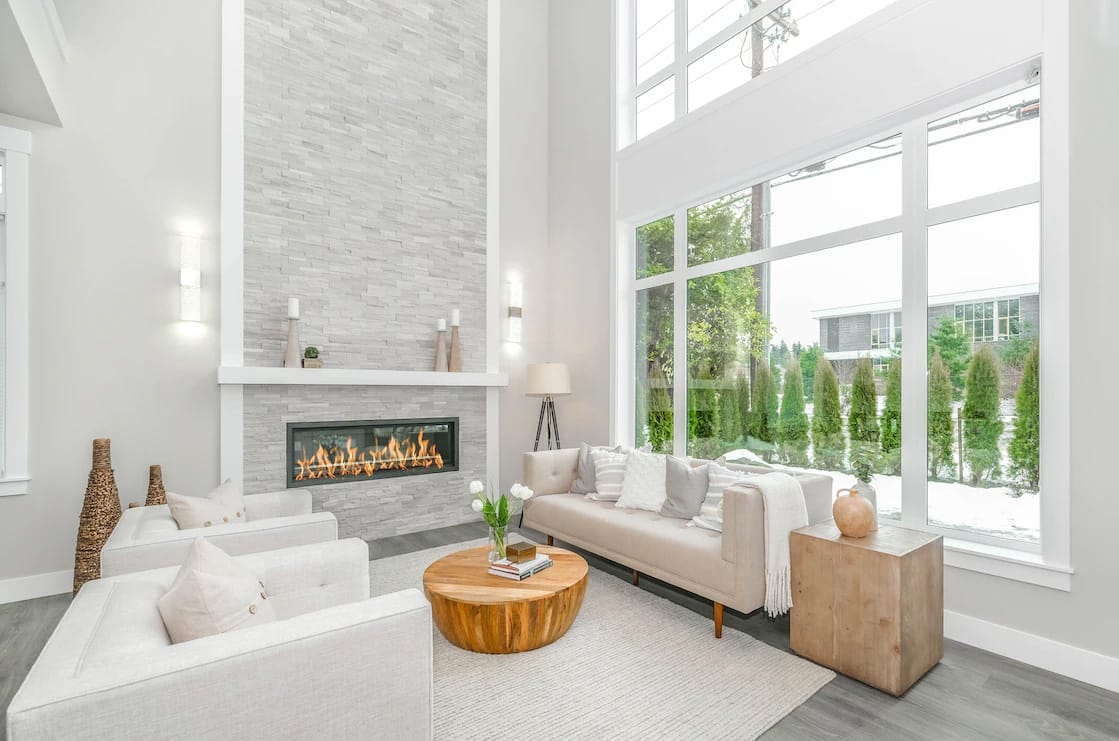 Luxurious living room with large windows, stone walls, and a fireplace