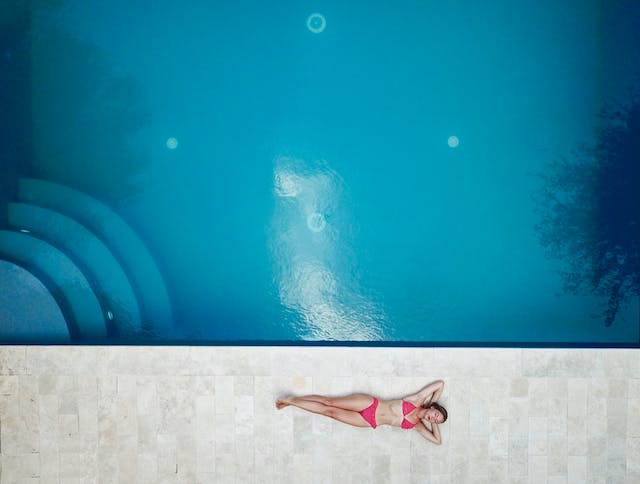 Woman in a pink swimsuit lying near a pool
