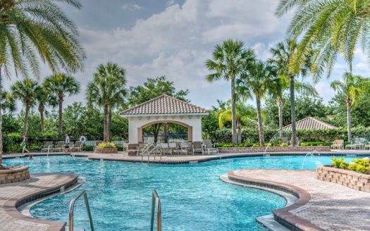 Huge outdoor pool with pool features for luxury properties surrounded by palm trees and deck chairs